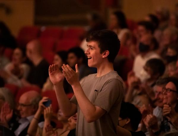 Photograph of a young man giving a standing ovation in Symphony Hall