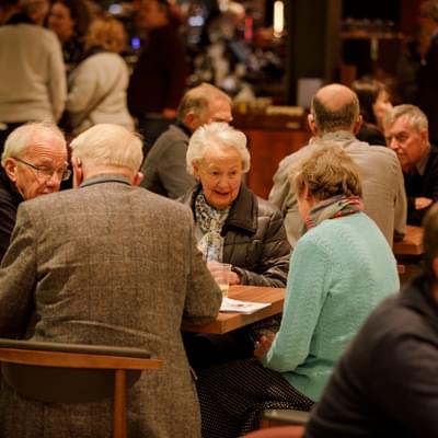 Photograph of a group of friends sitting and talking at a table in the Symphony Hall foyer