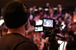 Photograph of a man filming the orchestra