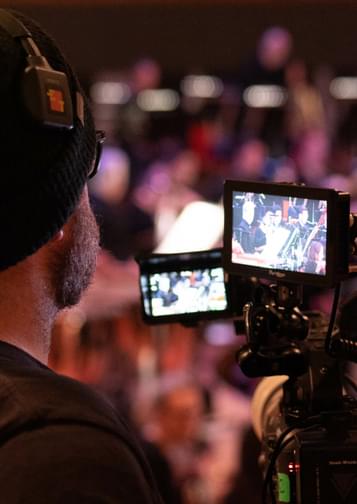 Photograph of a man filming the orchestra