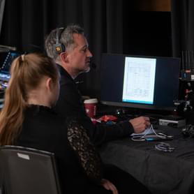 Photograph of a man and a woman watching a monitor backstage at Symphony Hall