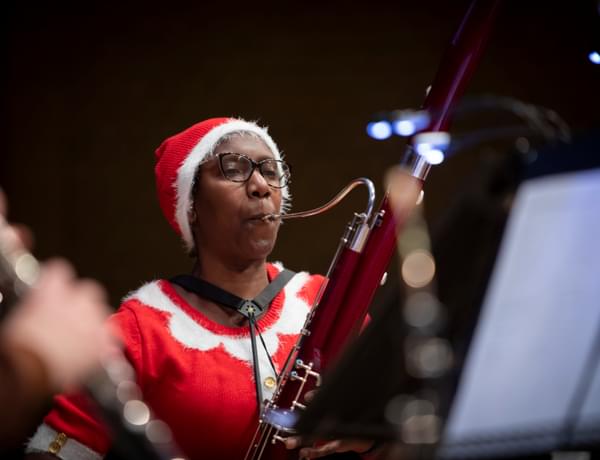Photograph of Margaret Cookhorn playing the ContraBassoon whilst wearing a Father Christmas outfit