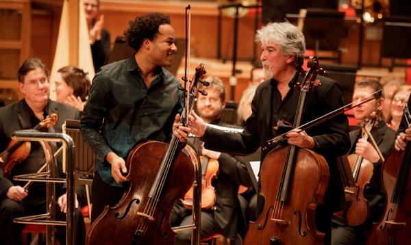 Photograph of Eduardo Vassallo and Sheku Kanneh-Mason chatting whilst taking a bow at Symphony Hall