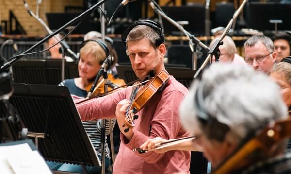 Photograph of viola player Adam Romer and other string players recording whilst wearing headphones