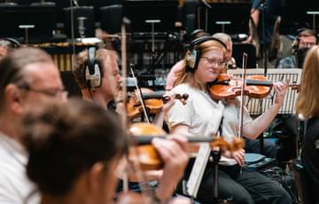 Photograph of violinist Georgia Hannant and other violinists wearing headphones during a recording session at CBSO Centre