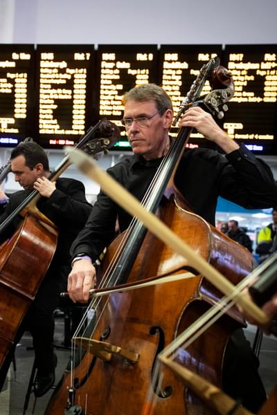 Photograph of Julian Atkinson and the double bass section performing at New Street station