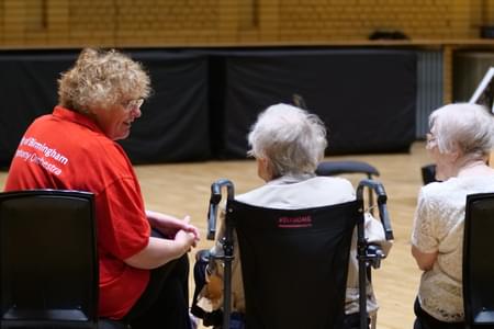 Photograph of harpist Katherine Thomas talking to an audience member at a Cuppa Concert