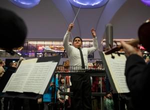 Photograph of a teenage boy conducting the orchestra at New Street Station