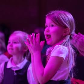 Photograph of a school child clapping whilst watching a performance