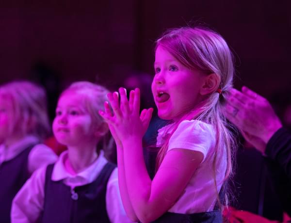 Photograph of a school child clapping whilst watching a performance