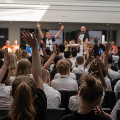 Photograph of children waving their arms in the air during a performance at Shireland CBSO Academy