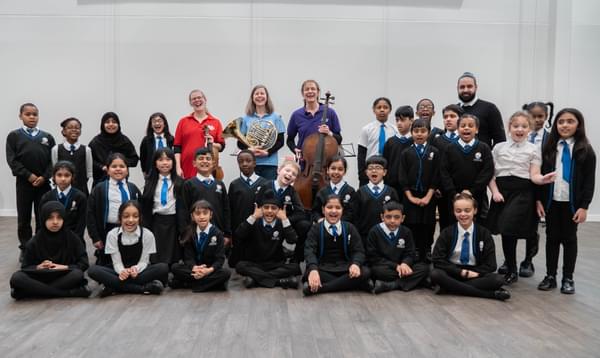 Photograph of a class of school children posing with CBSO Musicians