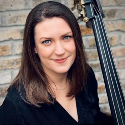 Headshot of double bassist Aisling Reilly. Aisling is stood with her double bass.