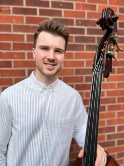 Photograph of Tom Neil smiling and holding a double bass