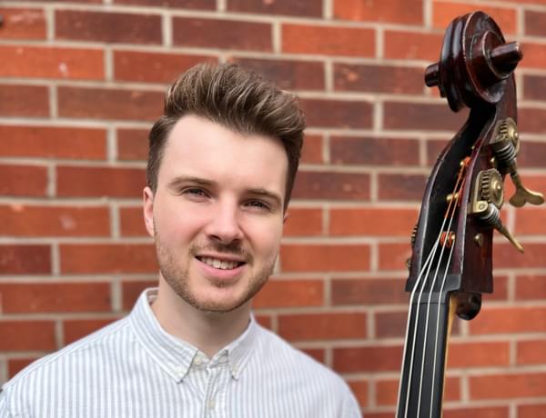 Photograph of Tom Neil smiling and holding a double bass