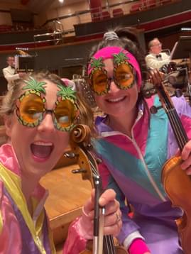 Photograph of Jessica Tickle and Amy Thomas dressed up in brightly coloured '80s shell suits before a performance