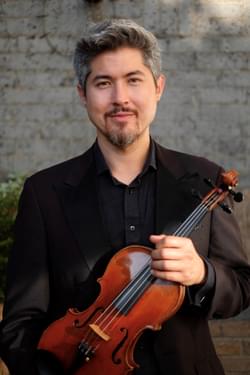Photograph of Tam Mott holding his violin.