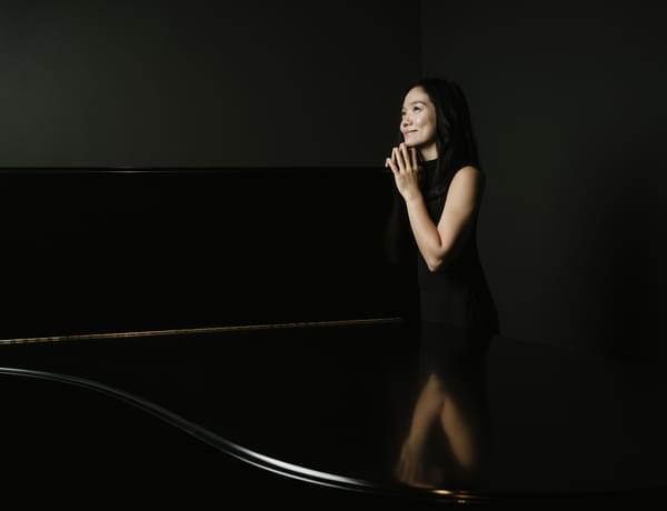 Photograph of Hisako Kawamura with a grand piano.