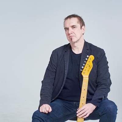 Photograph of Andy G Jones holding a guitar
