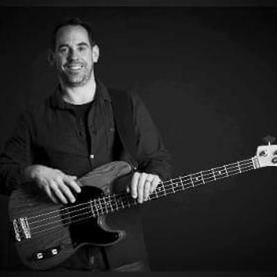 Photograph of Greg Hagger holding a bass guitar