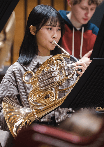 Photograph of a French Horn player in the CBSO Youth Orchestra.