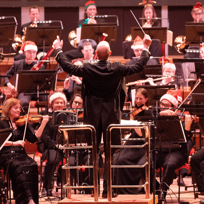 Photograph of Michael England conducting the CBSO, whilst the players wear Christmas hats.