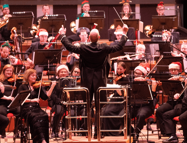 Photograph of Michael England conducting the CBSO, whilst the players wear Christmas hats.