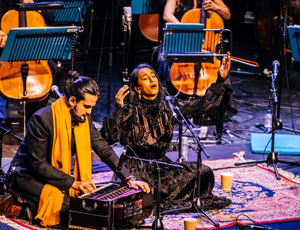 Photograph of two musicians sitting cross-legged on the floor to perform at Symphony Hall.