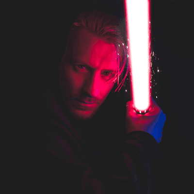 Photograph of a man holding a red lightsaber.