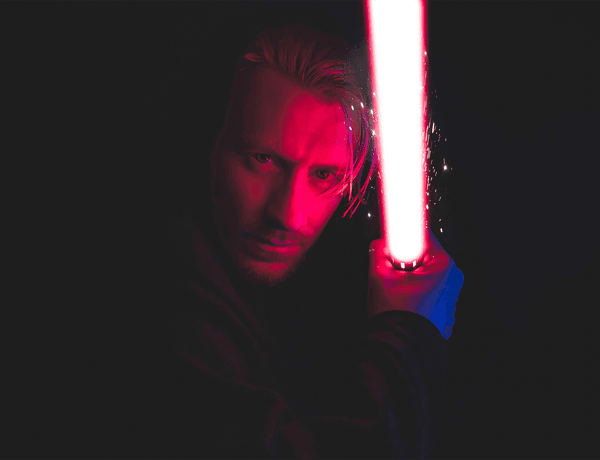 Photograph of a man holding a red lightsaber.