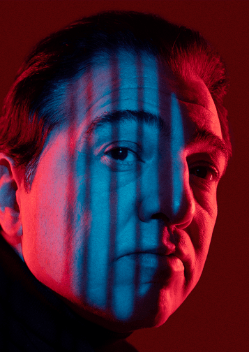 Photograph of Fazil Say with red and blue lighting playing across his face.