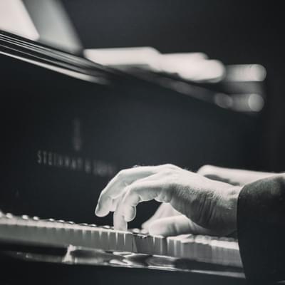 Photograph of a man's hands playing a piano.