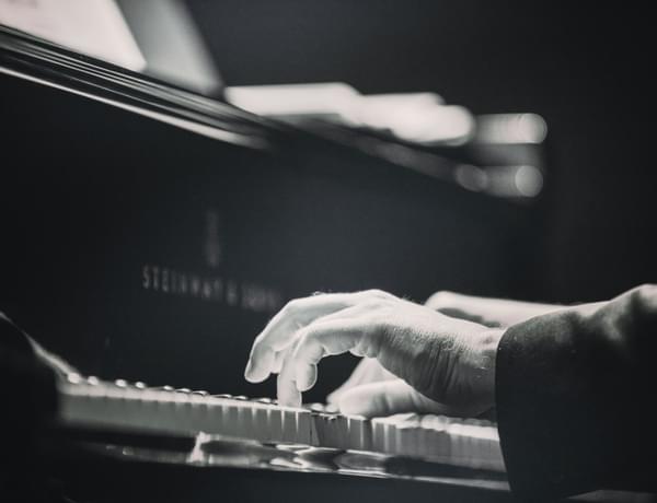 Photograph of a man's hands playing a piano.