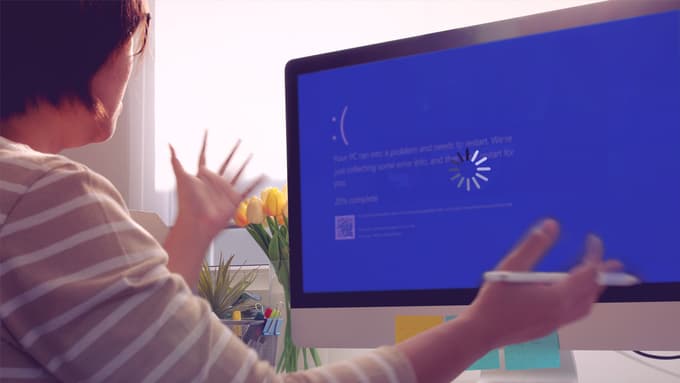 A woman looking frustrated in front of a computer showing an error message.