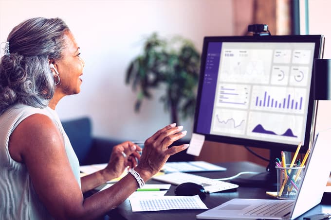 A woman working at a computer showing various charts and graphs.