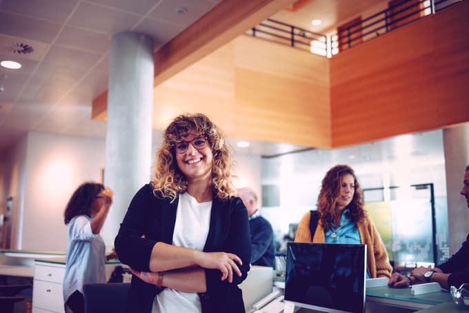 Smiling works inside of a modern office with natural lighting.