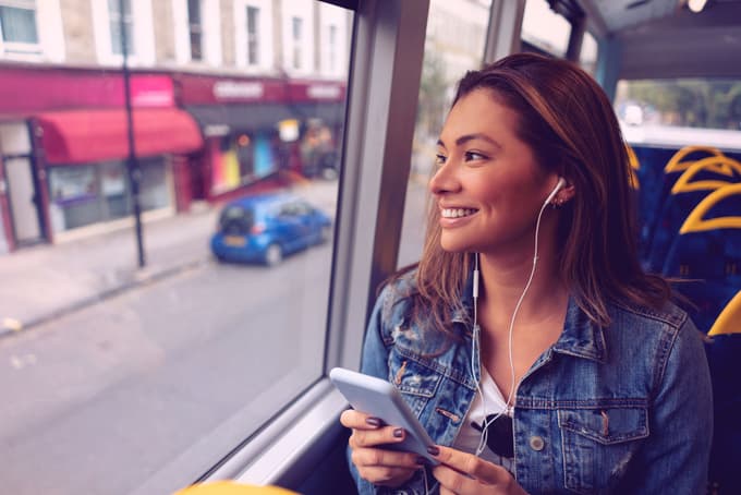 A woman listening to music or talking on the phone while riding a bus.