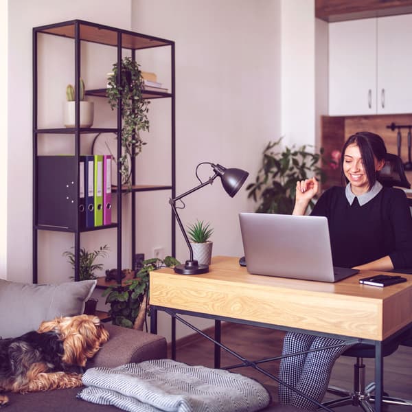 A woman at a laptop smiling while on a conference call.