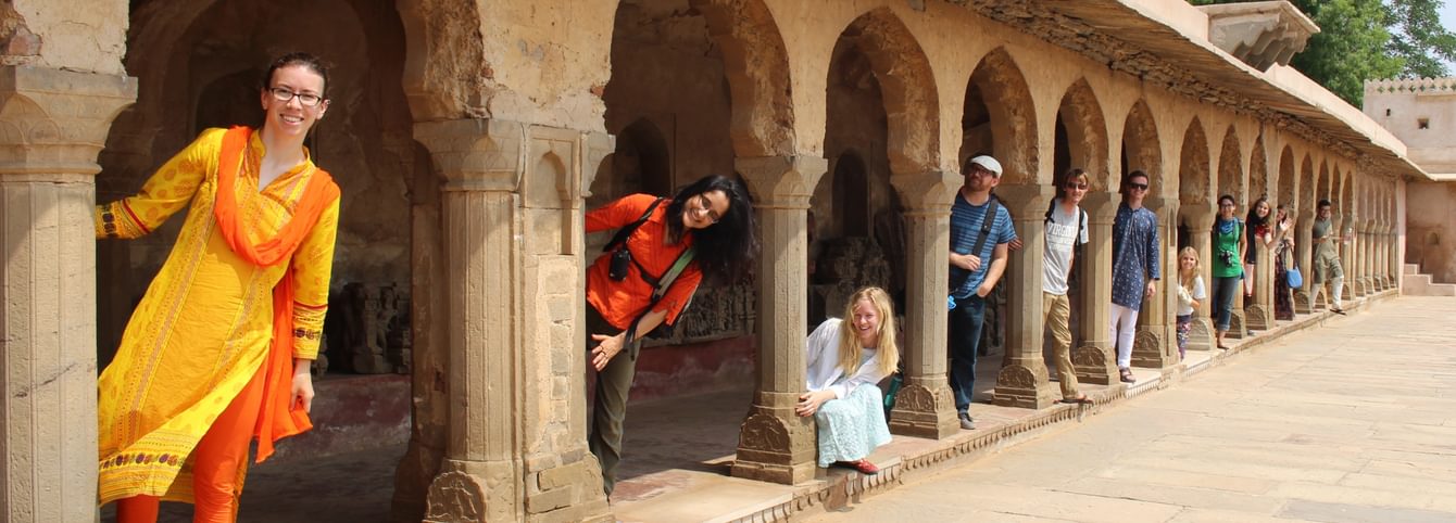 Hindi students peek out of arches at a historic site in India.