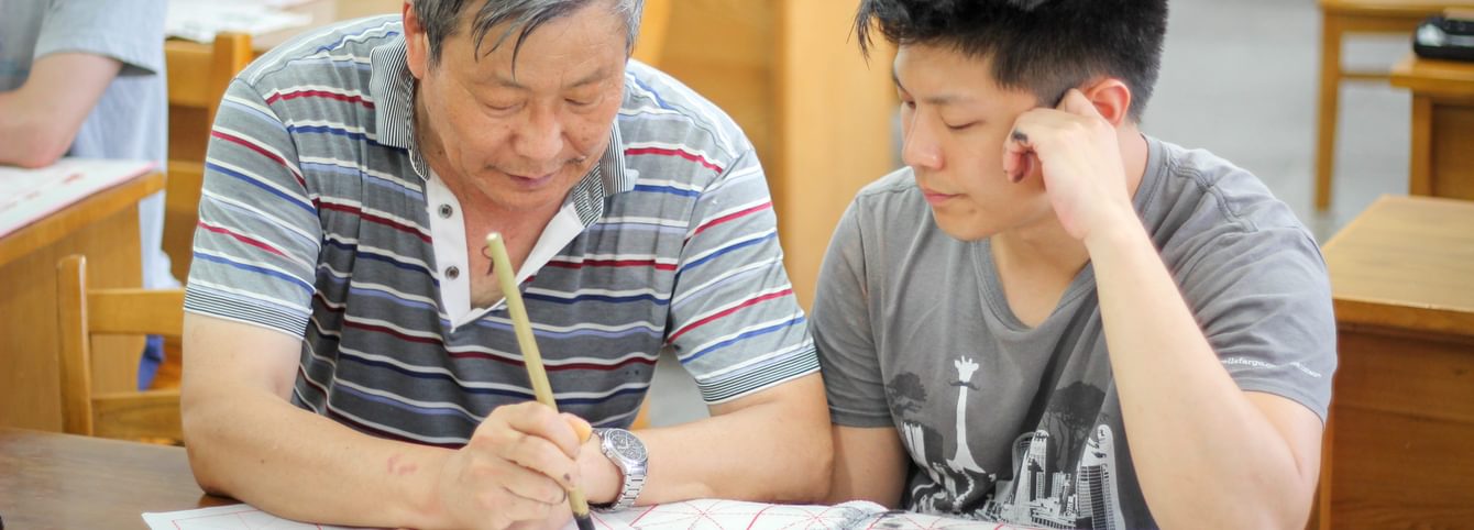 A CLS participant watches an instructor demonstrate Chinese caligraphy.