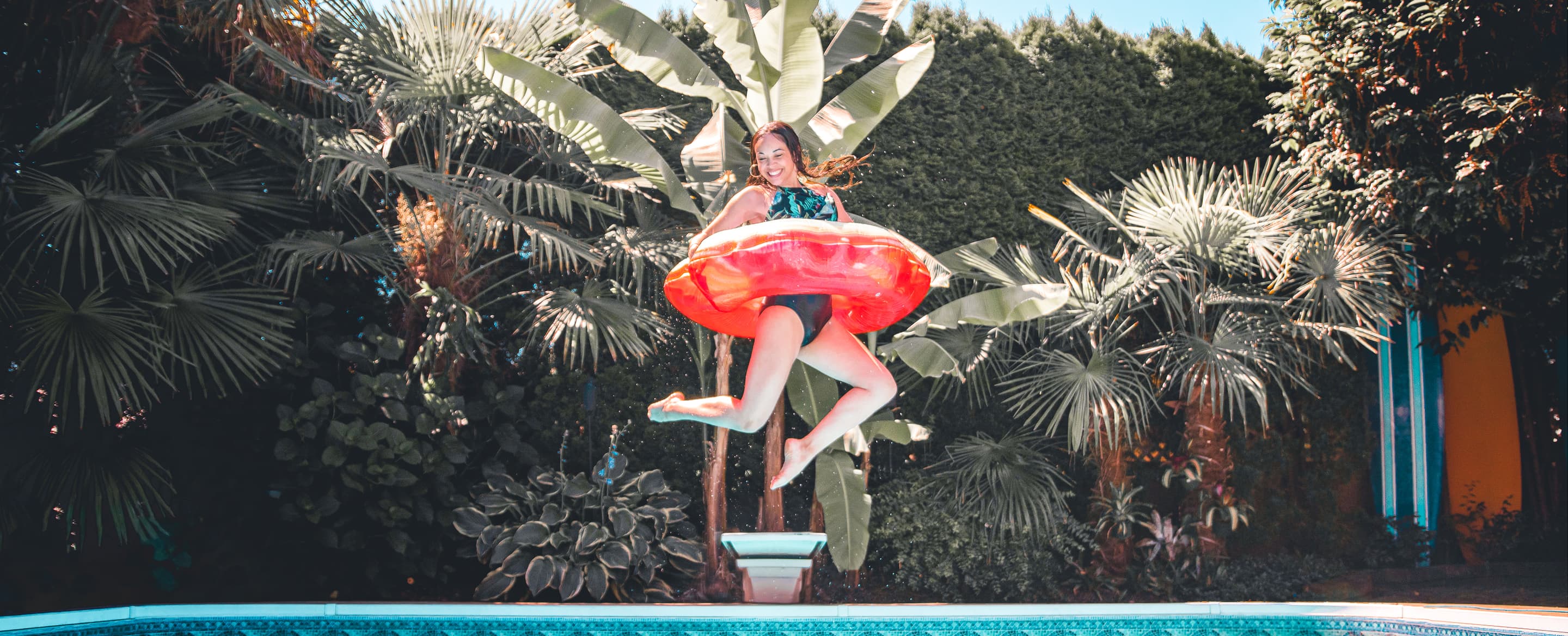 Happy woman with inflatable tube jumping into a sw D89 R7 QP