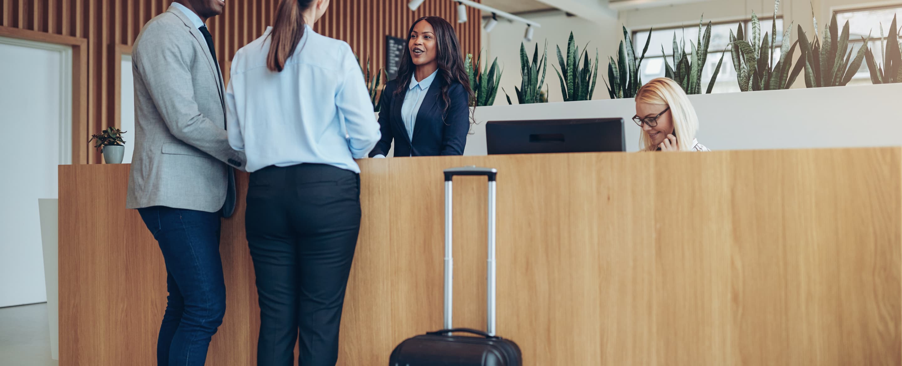 Two smiling guests checking in at a hotel receptio THFD9 XF