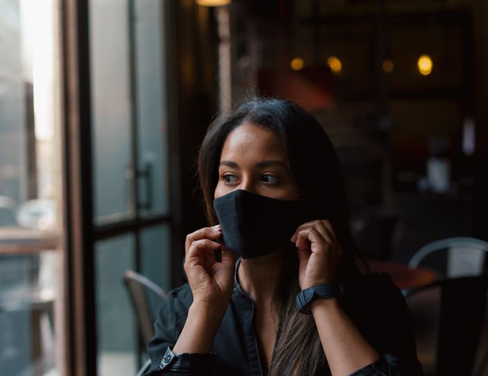 Young woman putting on face mask in coffee shop 3 P2 VMHP
