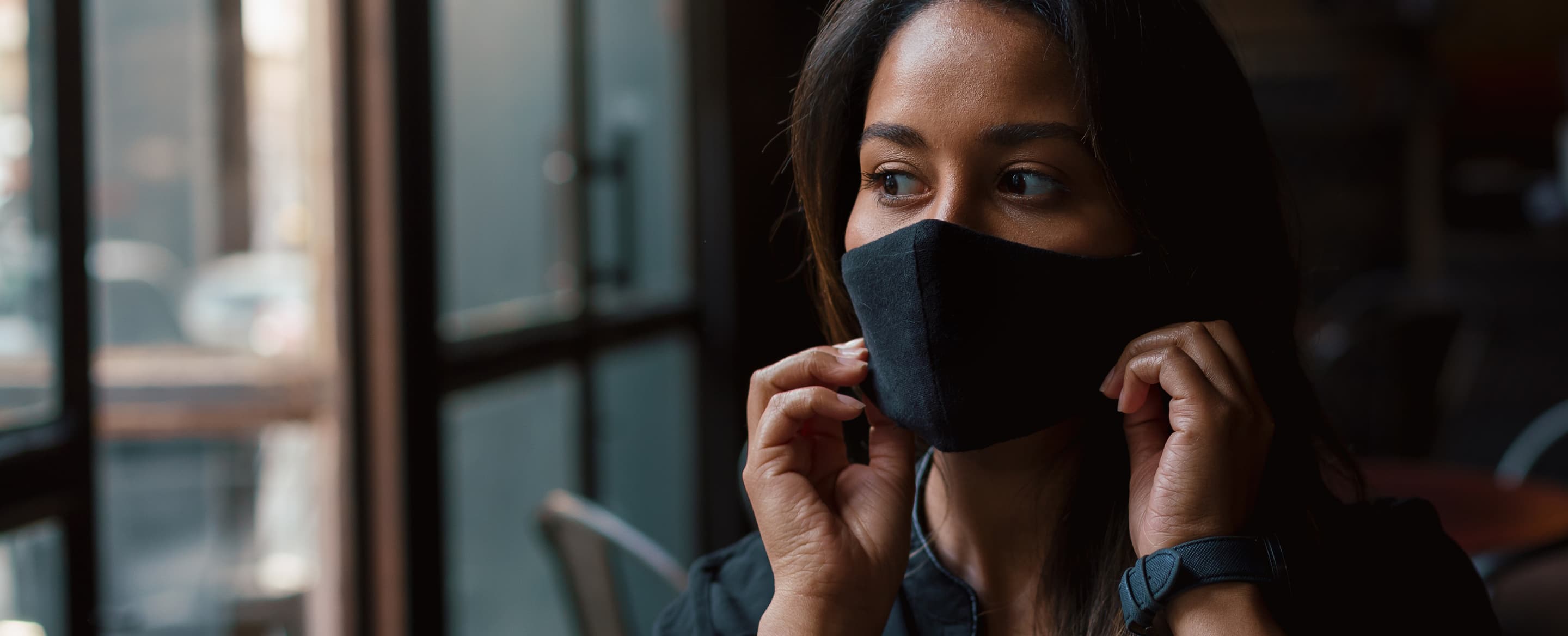 Young woman putting on face mask in coffee shop 3 P2 VMHP