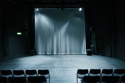 An empty studio space lit with grey lighting and empty chairs