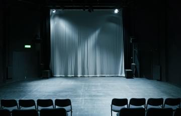 An empty studio space lit with grey lighting and empty chairs