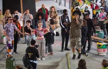 A group of young people perform a colourful show in a skatepark