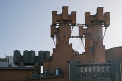 contact building exterior with the turrets and sign in the image. sunny blue skies behind the building.