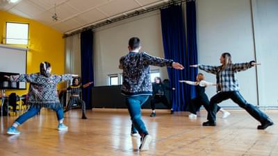 Young people hold warrior yoga poses in a rehearsal room