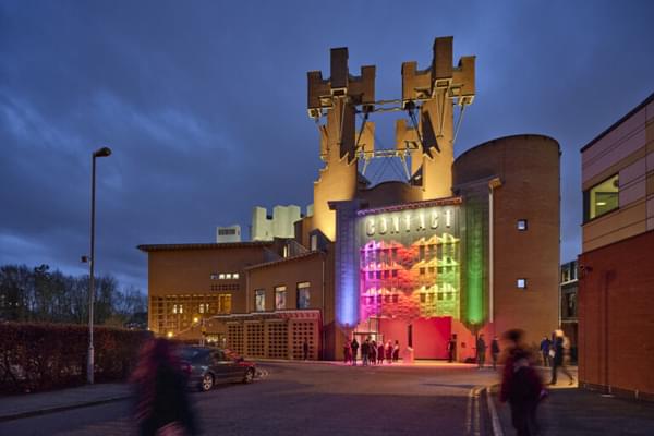 An image of the Contact building at dusk lit up in rainbow colours